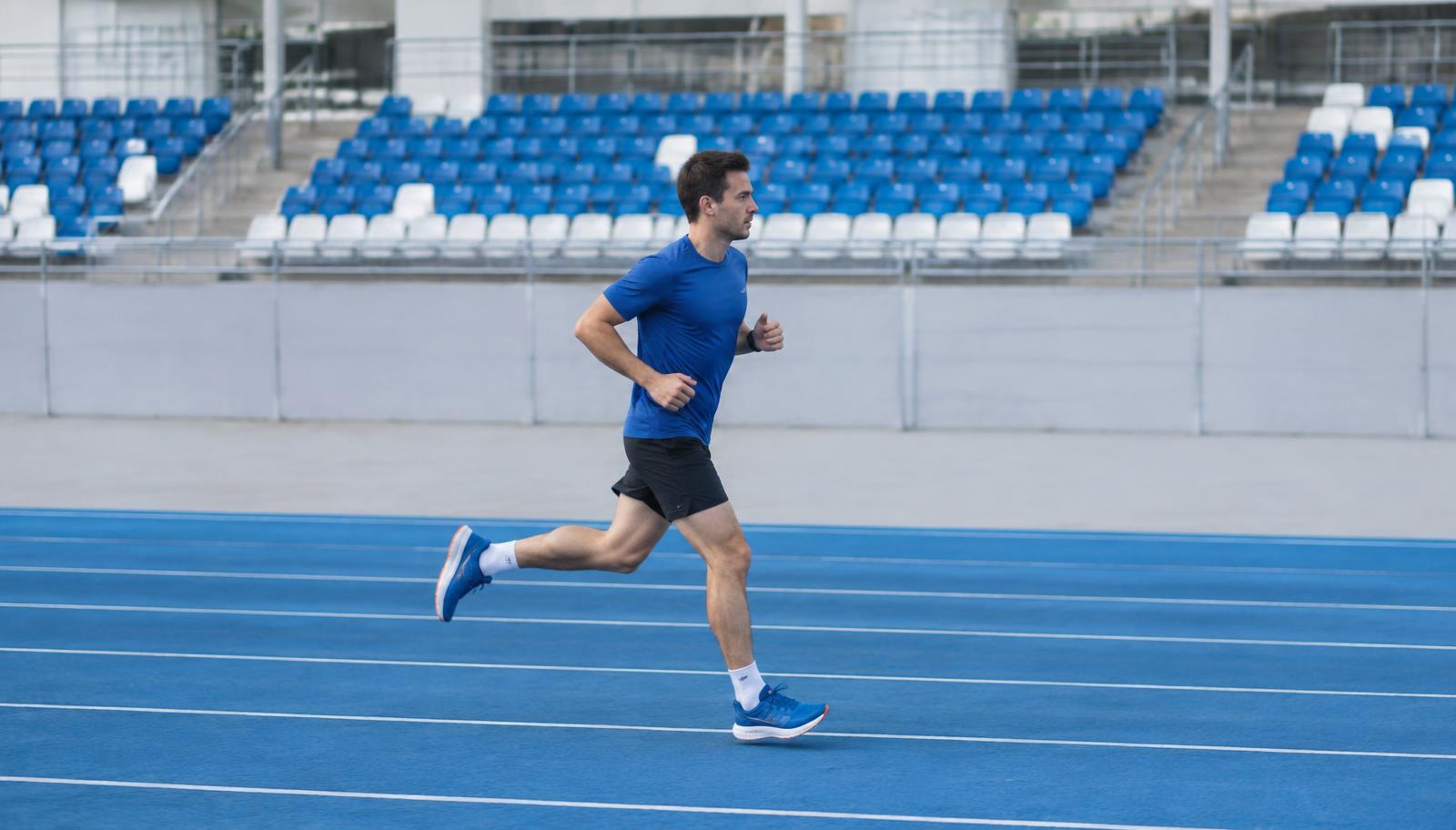 Corredor amador correndo na pista de atletismo azul